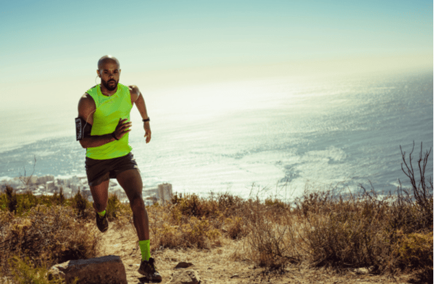 Full length of fitness man running over rocky trail on mountain.