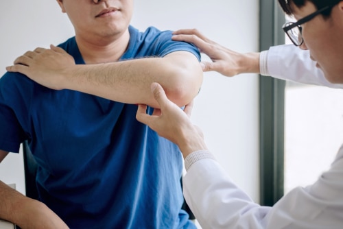 Doctor physiotherapist assisting a male patient while giving exercising treatment