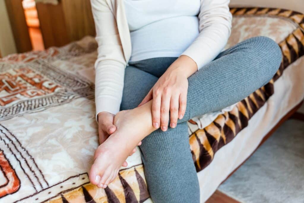 Woman sitting on bed and holding her ankle in pain and unsure how serious the injury is