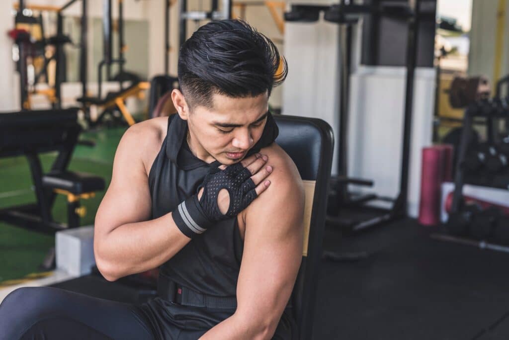 Man at gym touching shoulder with new pain that could be a SLAP tear