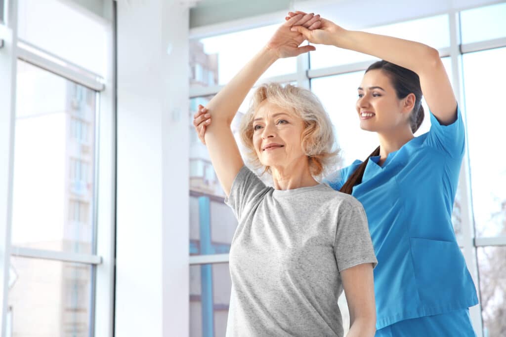 Doctor helping older woman with physical therapy to help with osteoporosis treatment