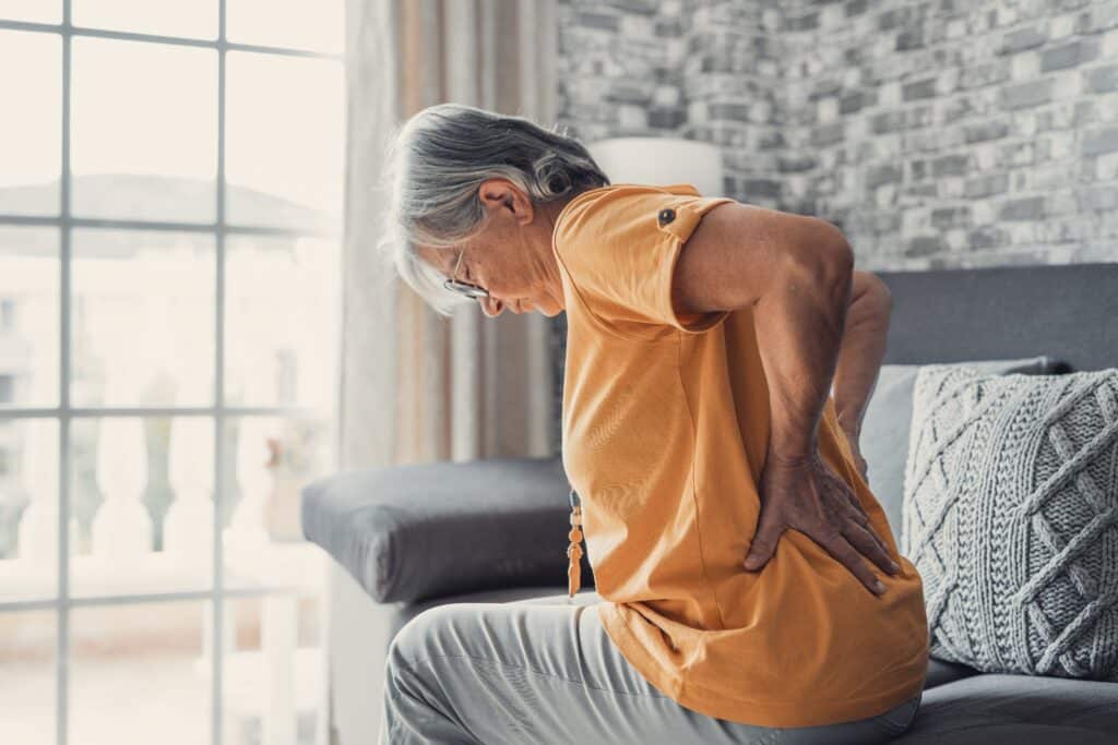 Older woman holding her lower back while experiencing sciatica pain