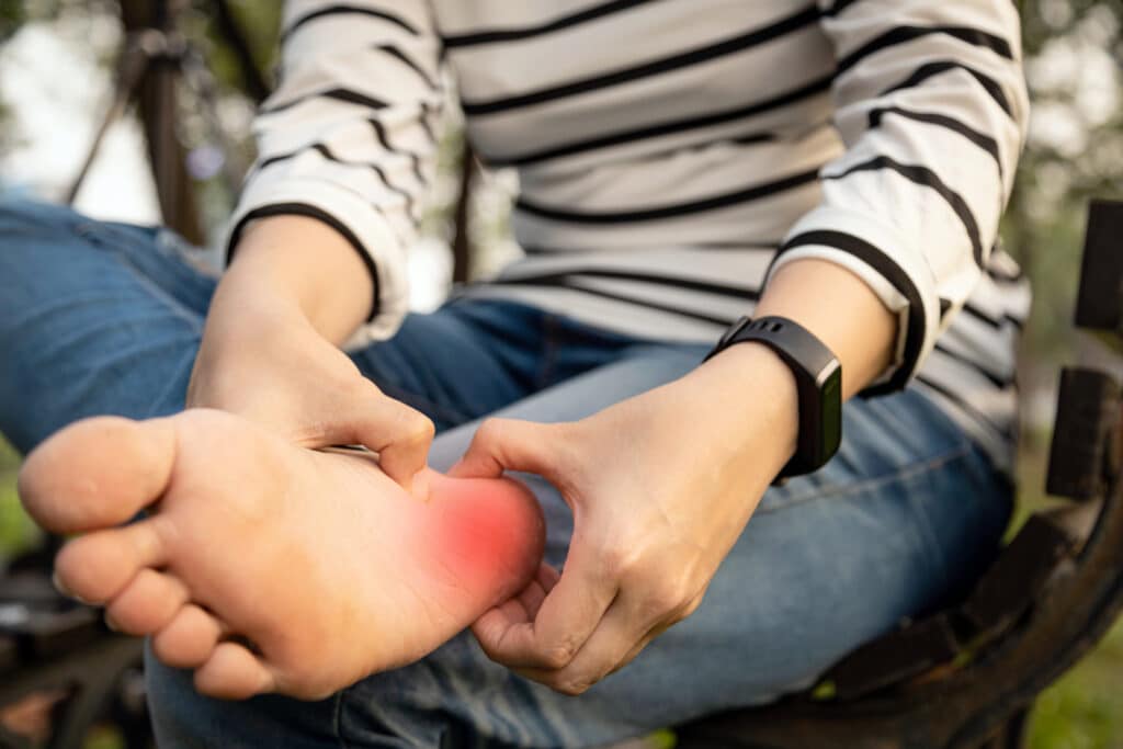 Woman holding her foot and experiencing pain in her heel from plantar fasciitis