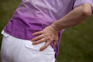 Person holding their hip while experiencing pain during walking.